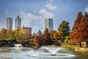 11-16 2020 - Tulsa USA - View from Central Park of downtown Tulsa Oklahoma on bright autumn day with colorful foliage and lake and fountains in foreground and vintage skyscrapers behind