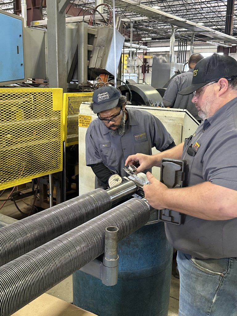 two men measuring the quality of finned tubes