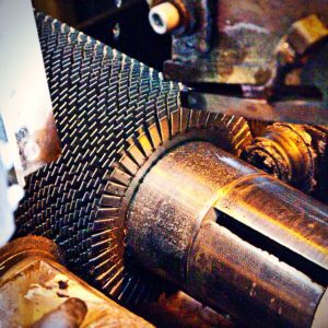 Close-up of finning machine forming serrated fins onto metal tube during manufacturing process